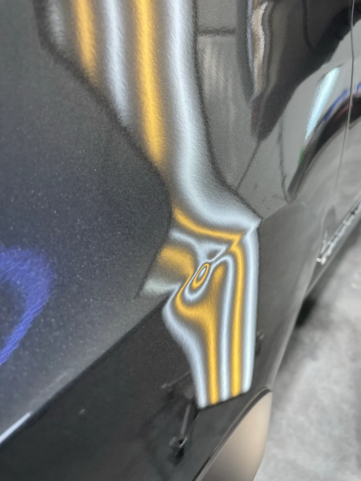 Black vehicle door panel with LED line-board revealing hail dents along the body line