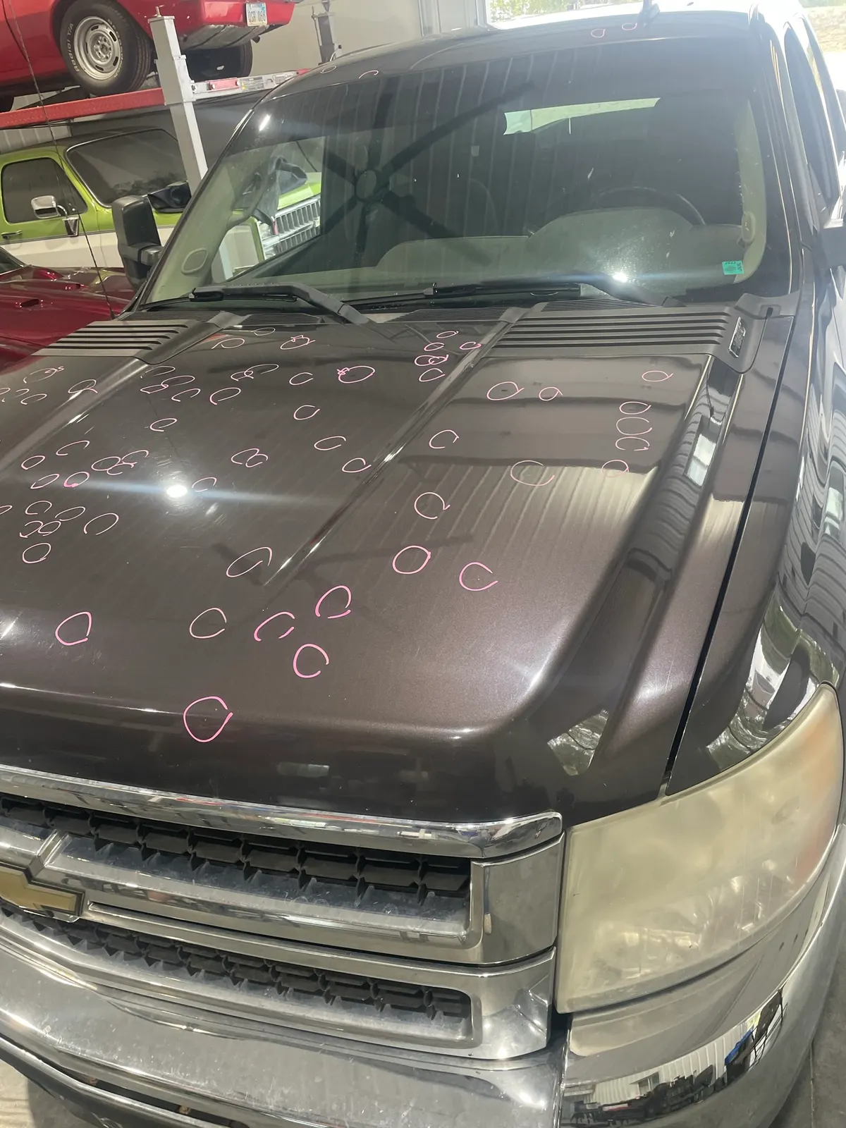 Chevrolet Silverado hood with hail dents circled in pink marker for adjuster documentation