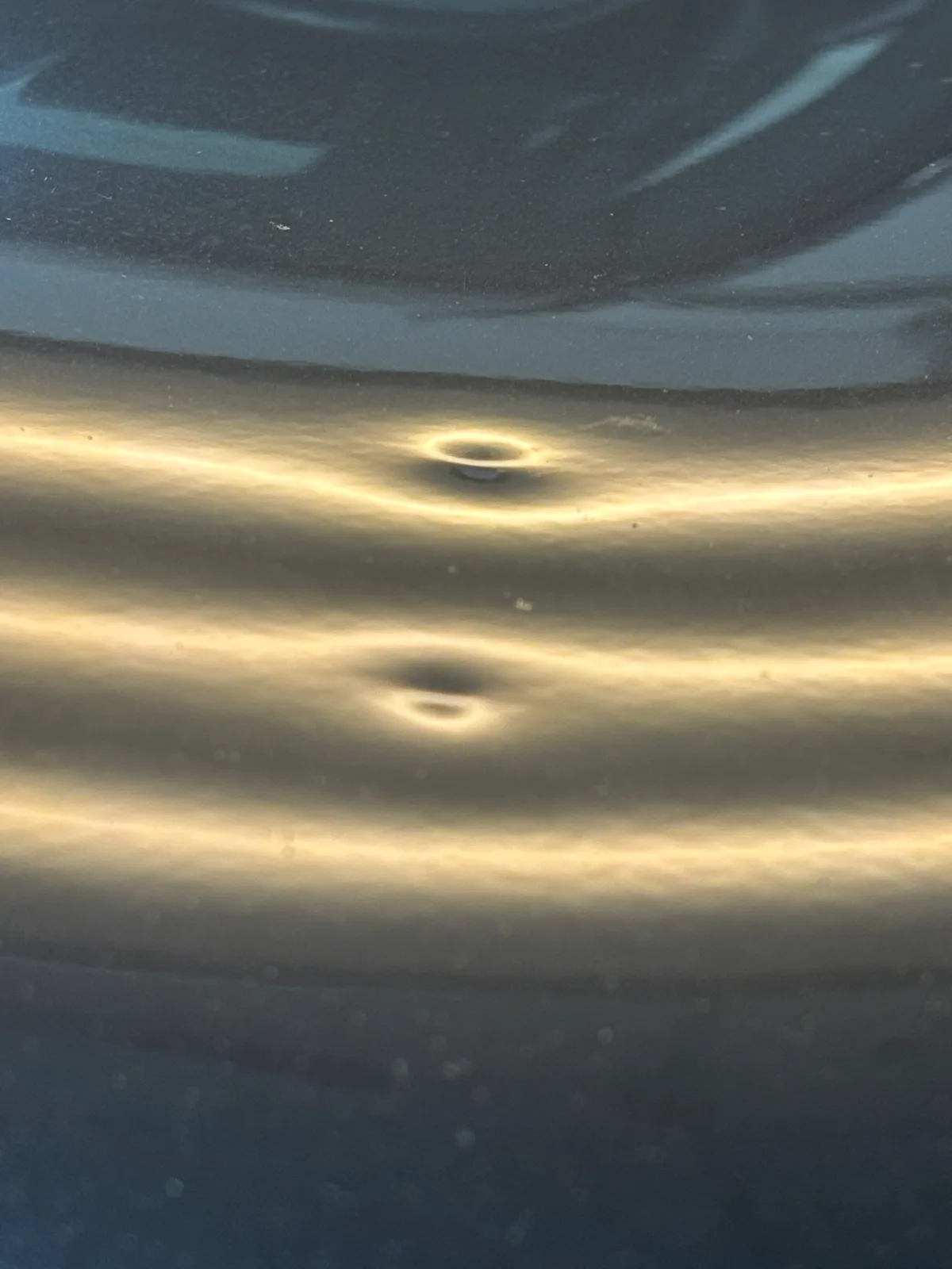 Light hail dents on a vehicle panel, revealed under raking LED light in Olathe, KS